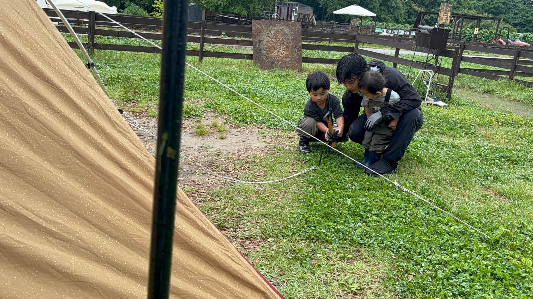 雨のなか、長男とペグ打ちをする渡部 裕貴