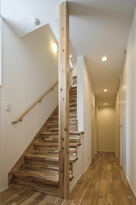 明るく開放感のある階段ホールは、脇に手洗ボウルを備えていて、手を洗ってから2階へ上がるのが家族の習慣。質感の豊かなアカシア材を階段の踏板・蹴込板にも使用しています。