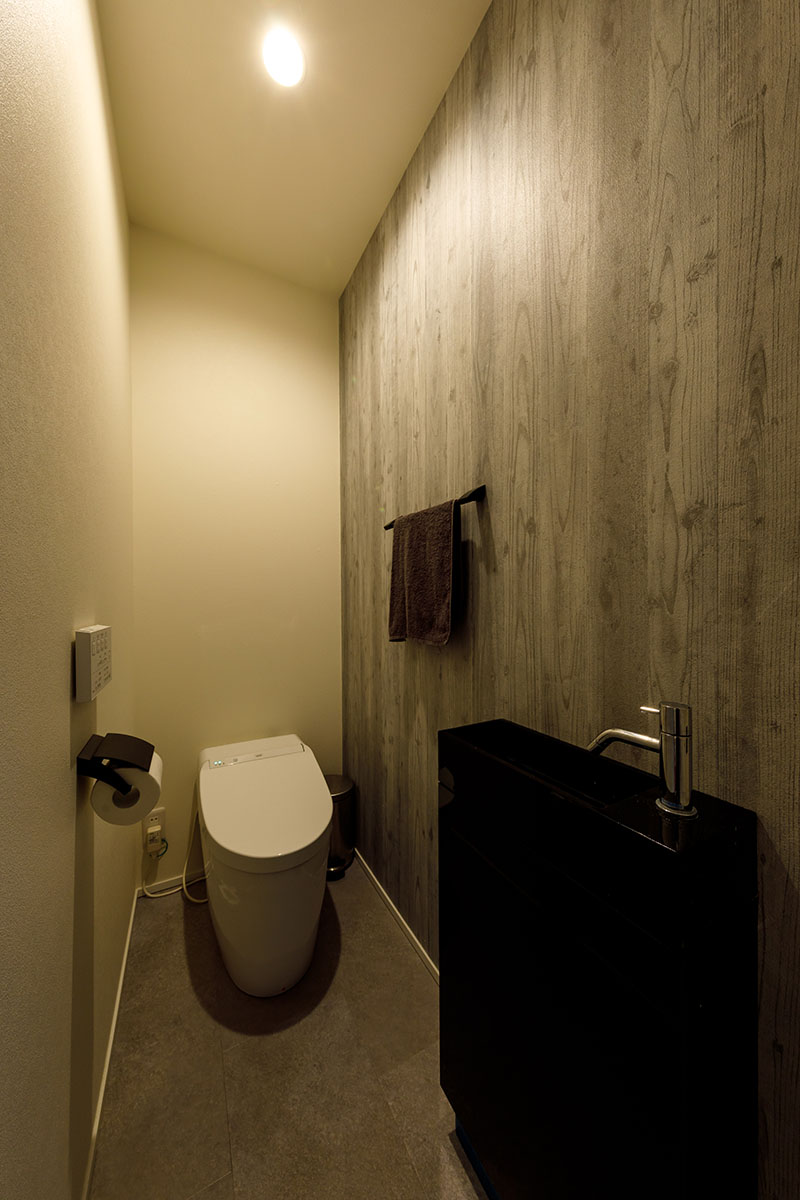 トイレはシャビーな木目のアクセントクロスに、フロアにはしっとりとした石調のデザインを組み合わせました。落ち着きのあるモダンデザインです。