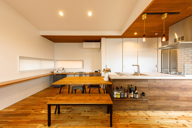 奥行きのあるダイニングキッチンは、ぐるりと回れるオープンなアイランドタイプで使いやすく、背面の大収納もあってキッチン回りもすっきり片付いています。キッチン天井の木の質感が空間のアクセントになっています。