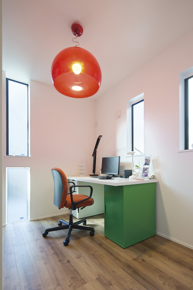 スリット窓を組み合わせたモダンデザインの居室。グリーンのデスクにオレンジの照明と椅子でポップな空間に仕上げました。