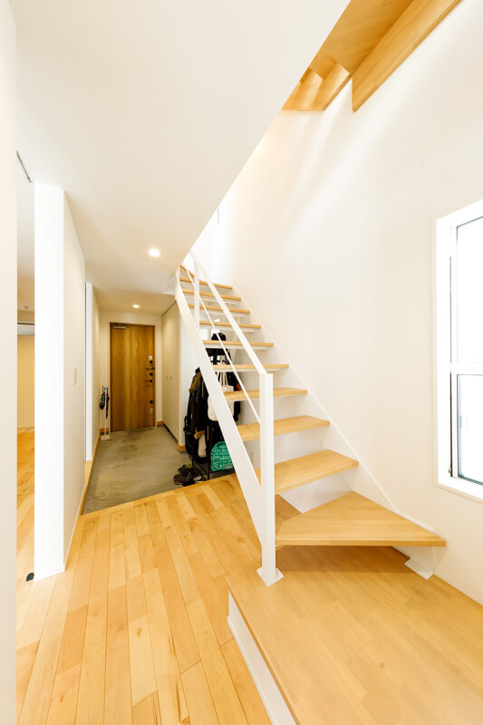 奥行きのある土間玄関から2階へと伸びるシースルー階段。開放的で家じゅうに光を通す設計が施されています。玄関脇の居室へ土間から直接入れる２WAYアプローチを採用しました。