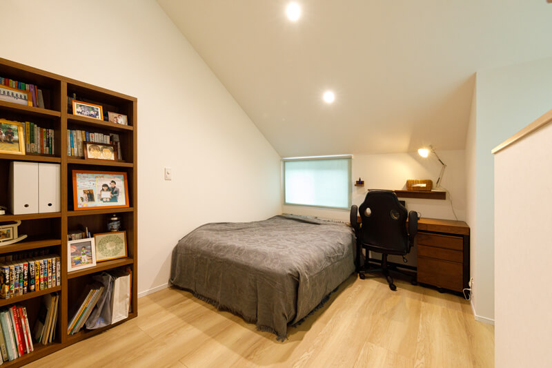 ワークスペースとして、こもって仕事に打ち込むことのできる寝室。勾配屋根で天井高を確保した、伸びやかで居心地のいい空間。